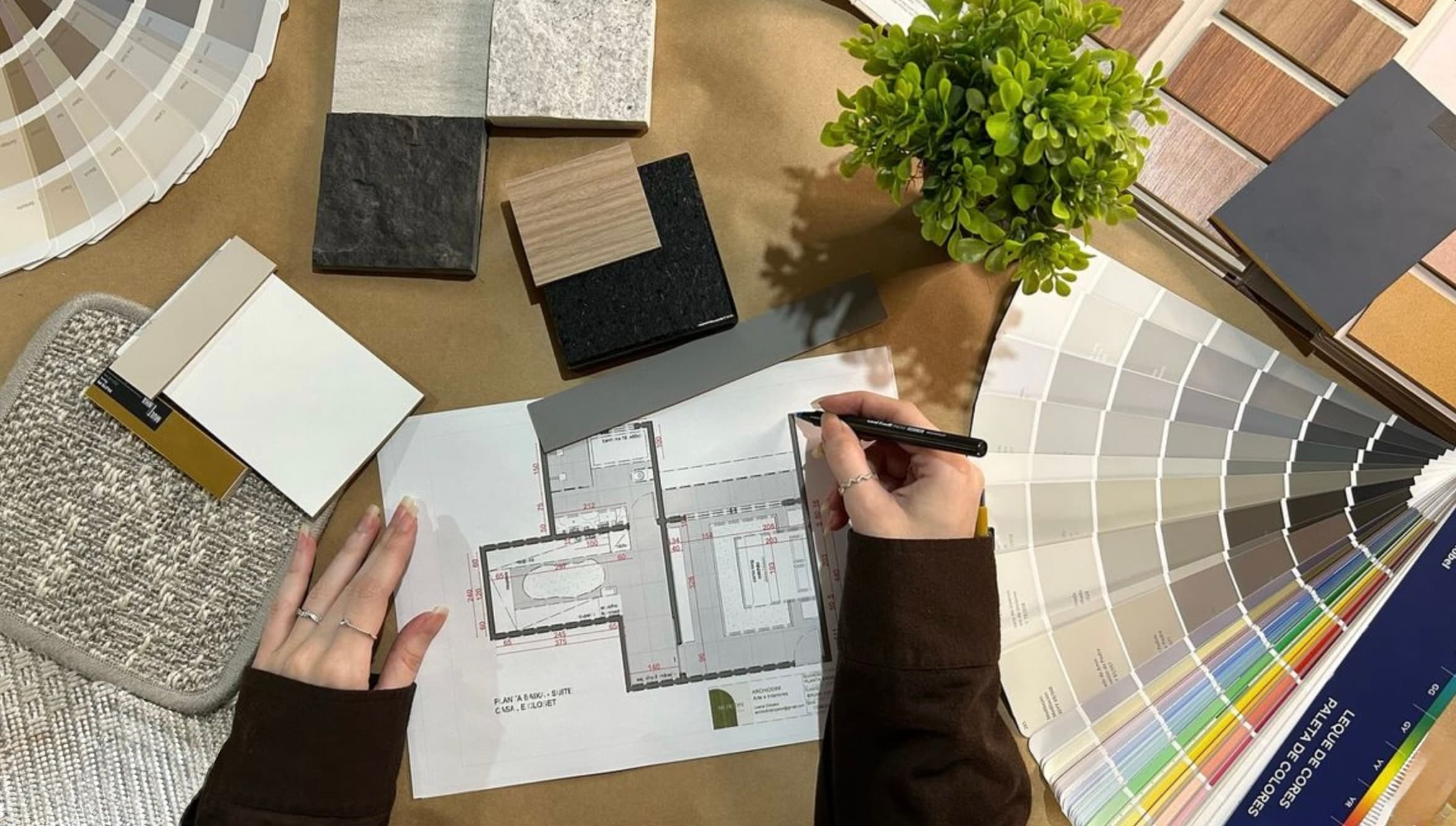 Plano de reforma sobre la mesa junto a muestras de materiales y paleta de colores